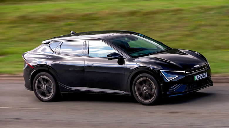 A black Kia EV6 in motion on a road with blurred grass in the background.