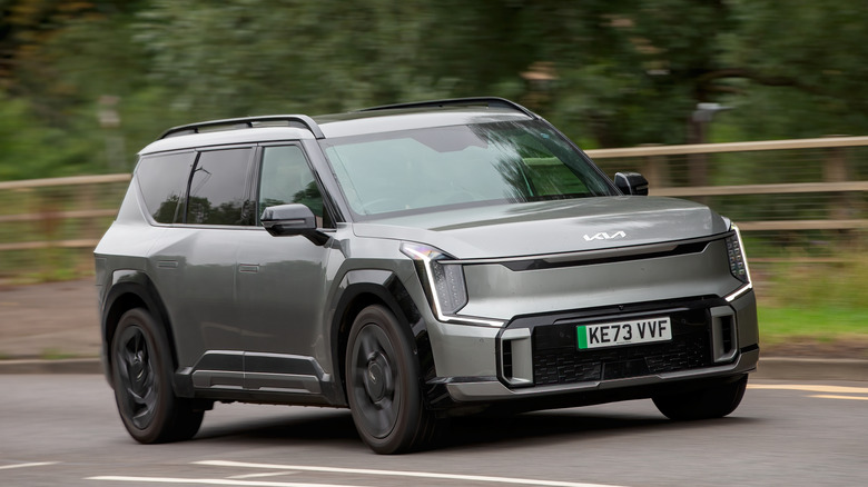 A gray Kia EV9 driving down the road.