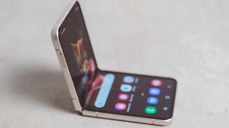 A folding phone is folded halfway to stand by itself.