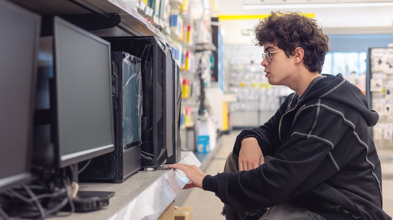 A boy shopping for monitors in an electronics store