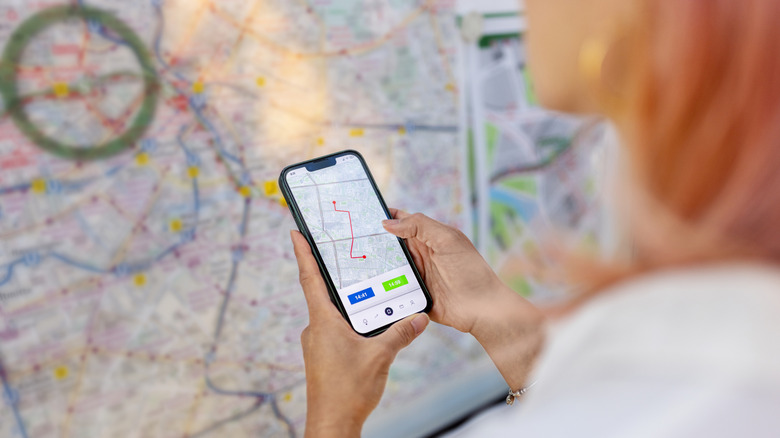 Woman checking map on phone infront of a train station map