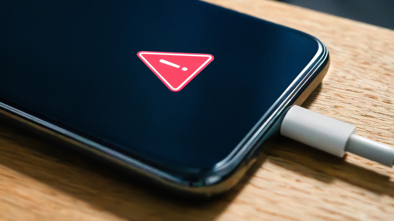 Smartphone displaying a battery warning while connected to a USB-C charging cable.