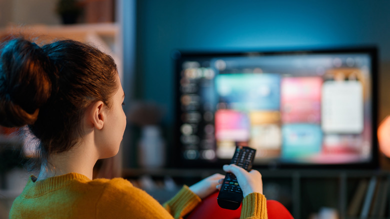 Person using a TV remote to browse content on a smart television.