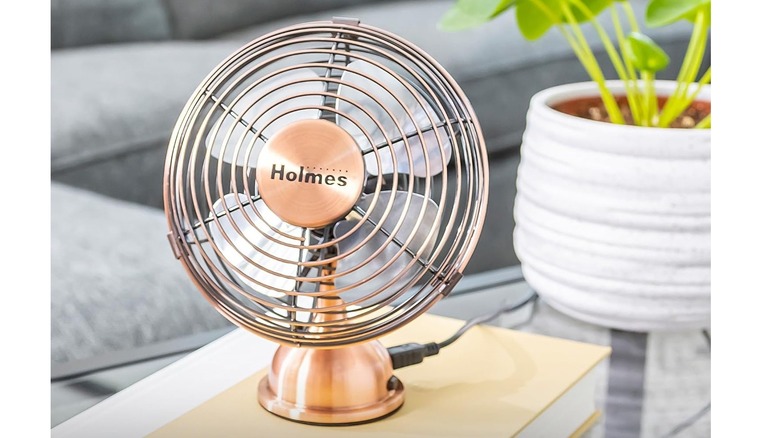 Holmes 4-inch desk fan with retro-inspired look on a table near a plant