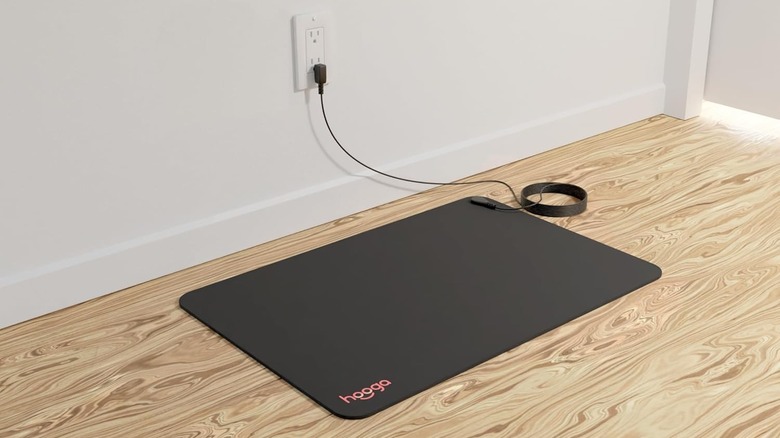 A Hooga Grounding Mat on a wooden floor, plugged into an outlet