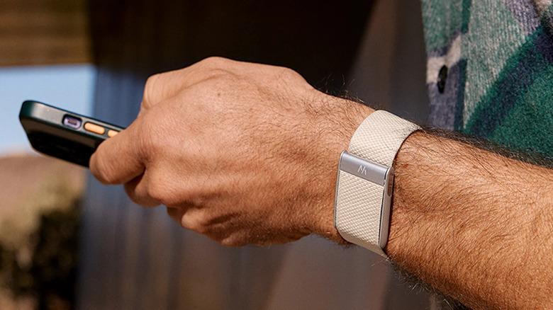 A person using their phone while wearing the Whoop 5.0 fitness wearable