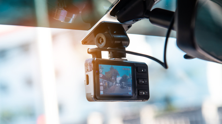 A dash cam attached to the windshield of a car.
