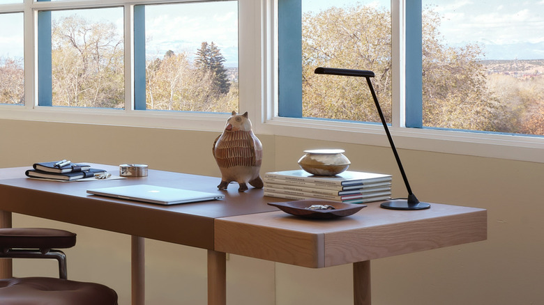 The Herman Miller Flute personal light in black on the corner of a desk.