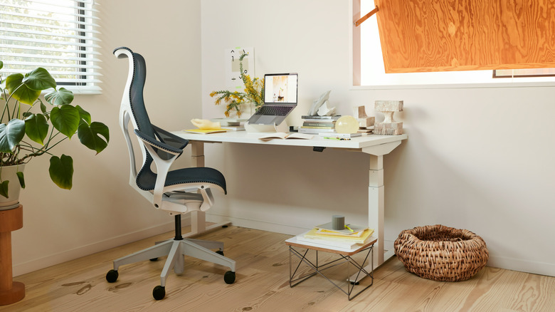 The Herman Miller Nevi sit to stand table various items on its surface in a home office.