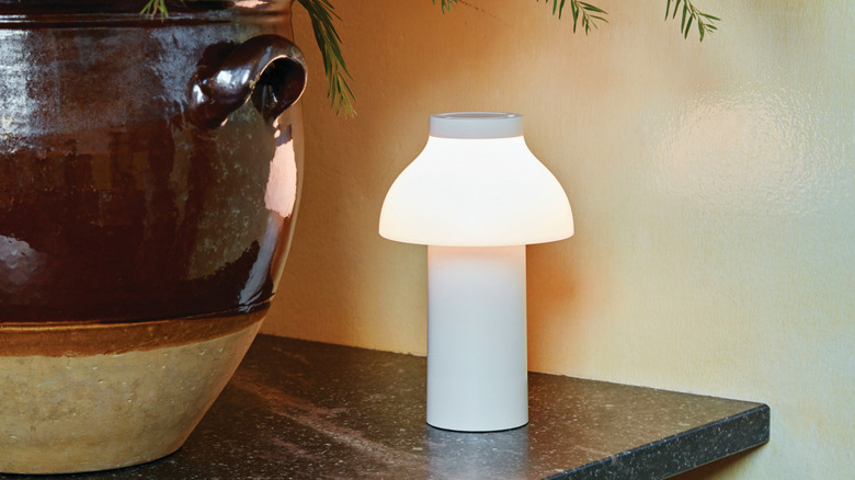 The Herman Miller PC portable lamp on the corner of a flat surface.
