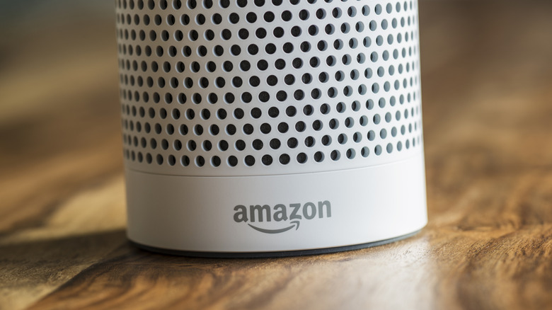 The bottom of a white Amazon Echo speaker featuring a gray Amazon logo on a wooden surface.