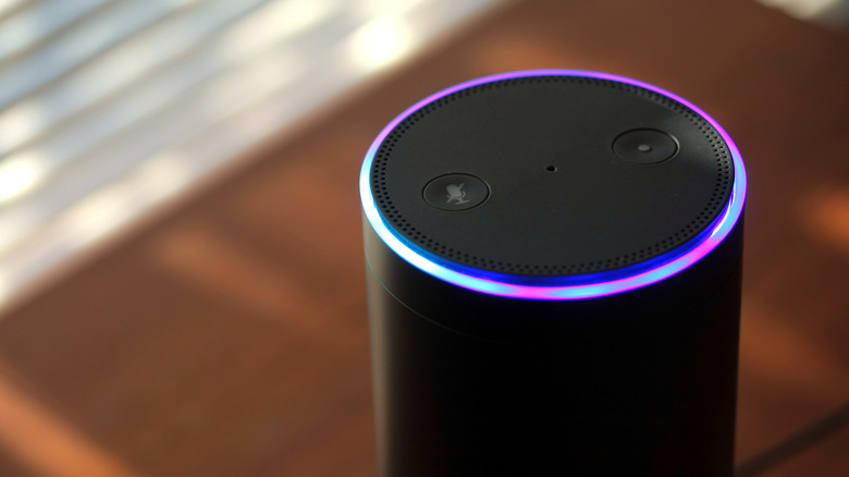 A black Amazon Echo speaker with a ring of blue and pink light on the upper edge.
