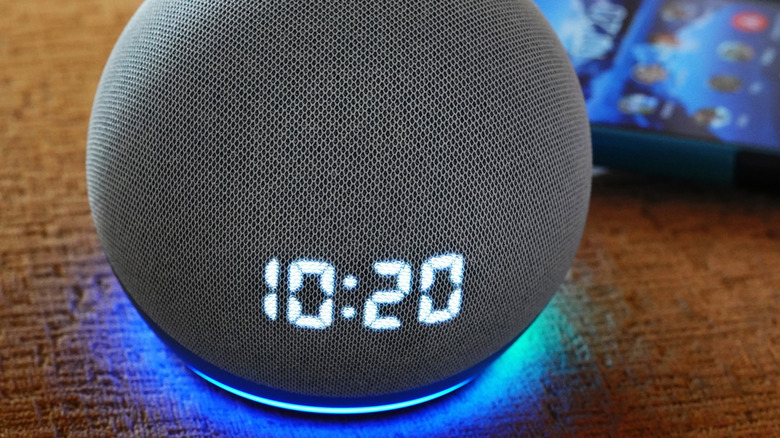 An Amazon Echo Dot speaker on a table displaying the time 10:20.