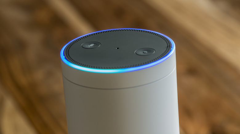 A white and gray Amazon Echo speaker with a blue light around its upper rim.