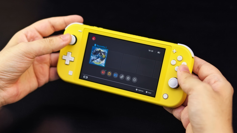 Hands hold a yellow Nintendo Switch Lite.