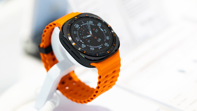Close-up of a Samsung Galaxy Watch Ultra with an orange band against a blurred white background