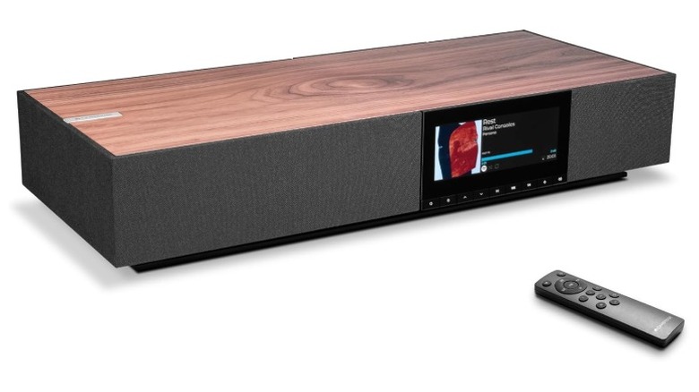 A product render of the Cambridge Audio Evo One all-in-one speaker system with its remote in front.