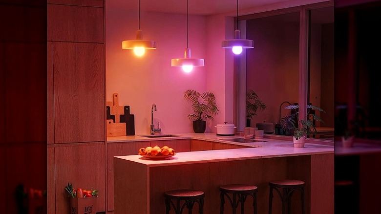 Three different colored lights are hanging on kitchen lamps.