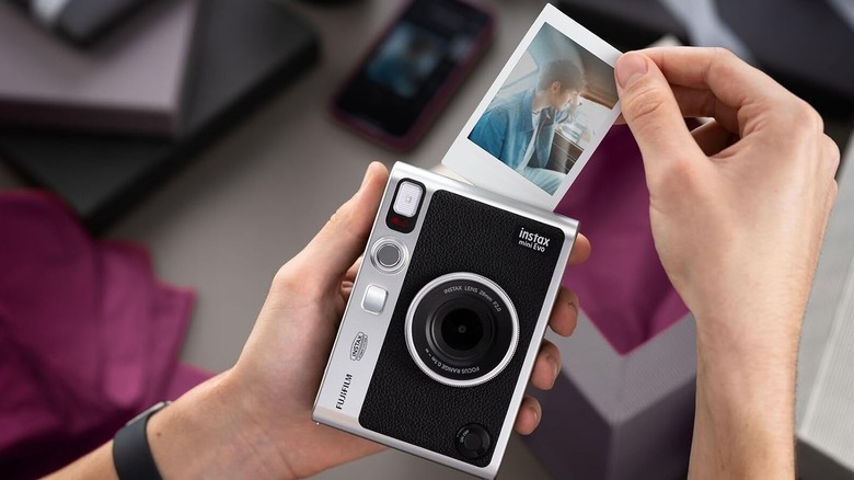 A person printing a photo from the Fujifilm Instax Mini Evo instant camera.