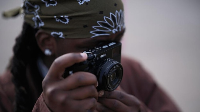 A person using the Fujifilm X100VI digital camera to take a photo.