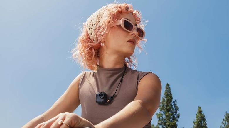 A person wearing the Insta360 GO Ultra hands-free camera around their neck.