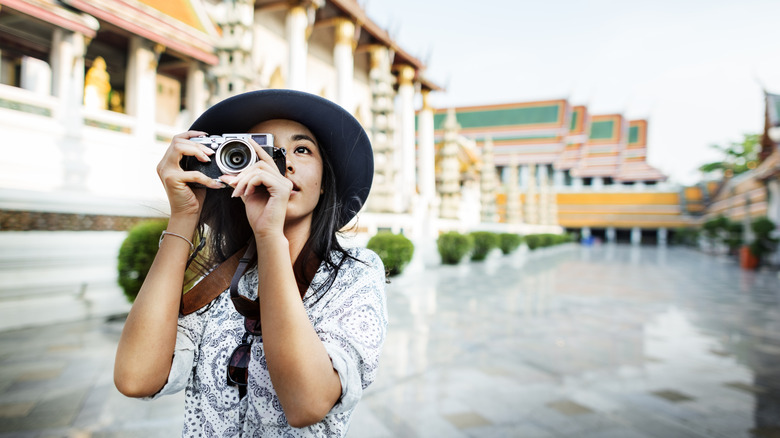 A tourist take a photo at a tourist location using a camera.