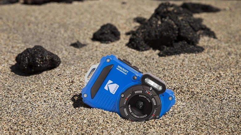 The Kodak PixPro WPZ2 waterproof camera partially buried in the sand.