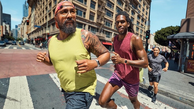 A group of men wearing the Fitbit Charge 6 while running on the street.
