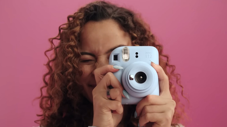 A person taking a photo with the Instax Mini 12