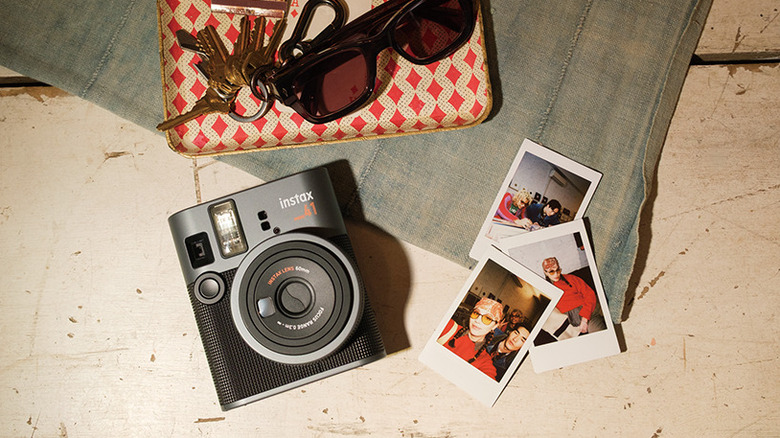 Fujifilm Instax Mini 41 kept on a table with three printed photos beside it