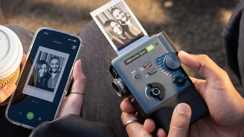 A person printing a photo from an instant camera