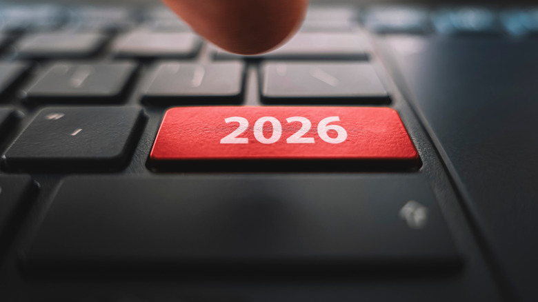 A finger hovers over a keyboard button labeled with the year 2026.