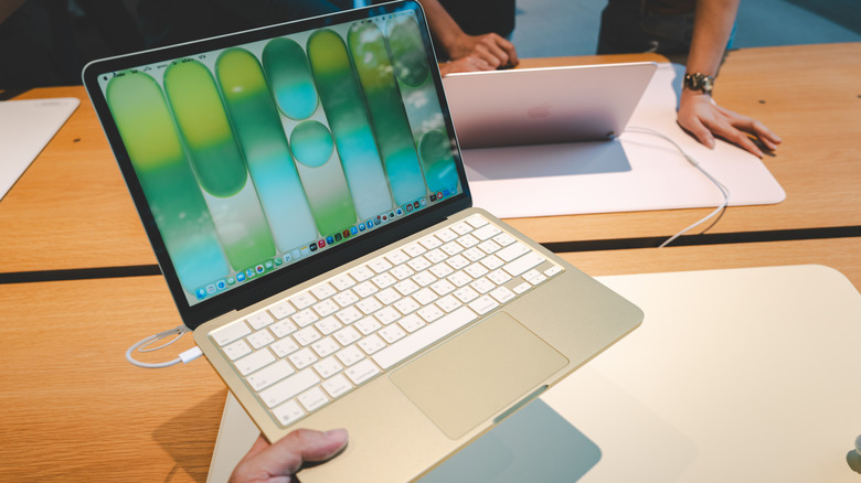 A person holds an Apple MacBook Neo in one hand.