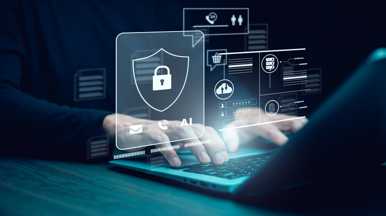 Person with hands on laptop with a hologram with security icons