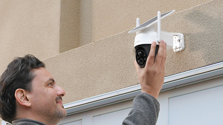 A man installing the AOSU Solar Camera C9C outdoors.
