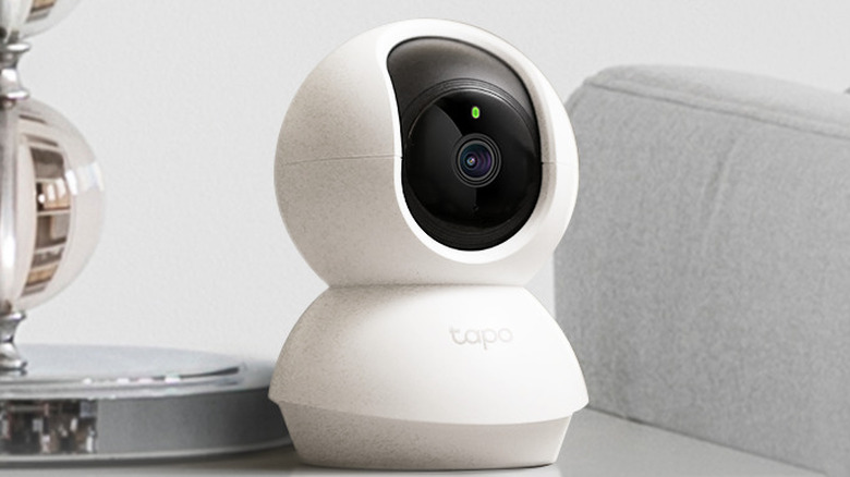 The TP-Link Tapo C200 on a desk beside a lamp.