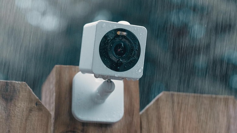 The Wyze Cam OG attached to an outdoor wooden fence, getting wet in the rain.