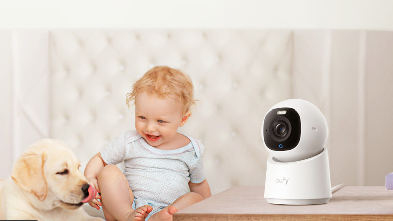 The Eufy Indoor Cam E30 security camera on a desk, watching over a baby and a puppy.