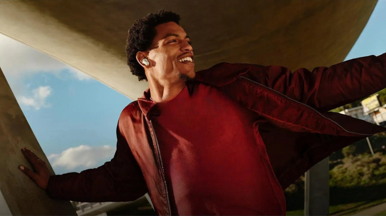 A man stands beneath an underpass while wearing a pair of Bose earbuds.