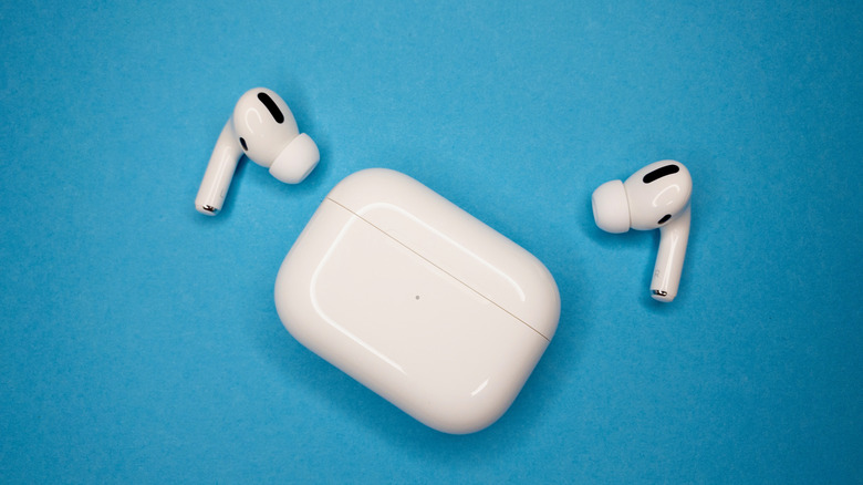 A set of AirPods Pro on a blue background next to their charging case.