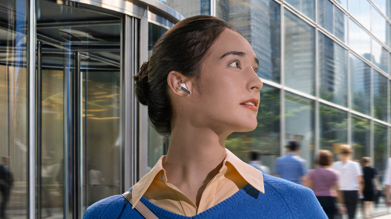A woman wearing the Samsung Galaxy Buds4 Pro and looking off-camera in front of a glass building.
