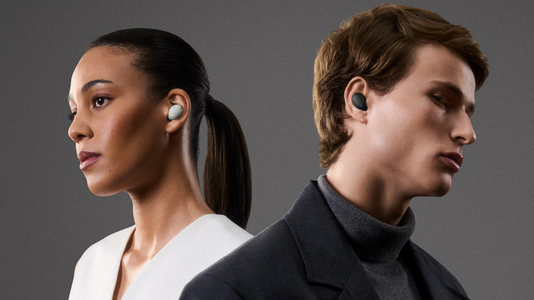 A man and a woman look in opposite directions while wearing Sony earbuds in two different colors.