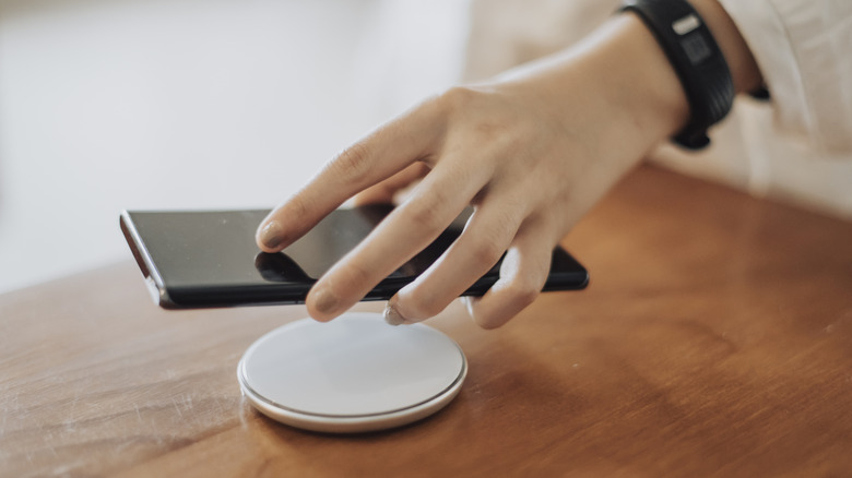 A person placing a smartphone on a wireless charger.