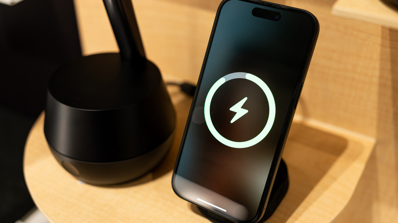 A smartphone charging on a wireless charging stand.