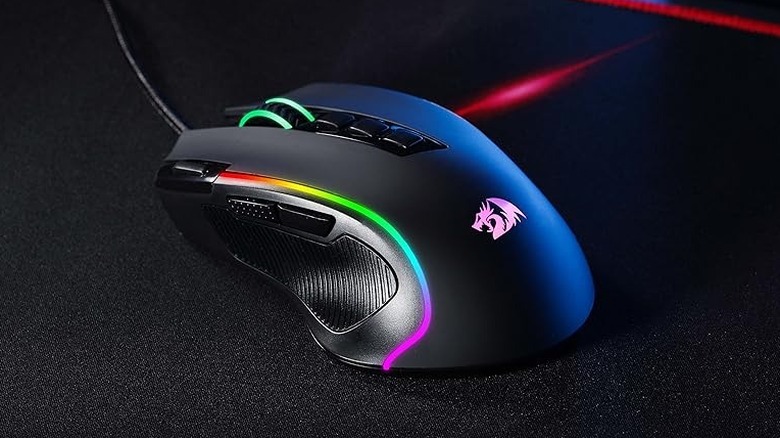 A black Redragon M612 Predator gaming mouse on a desk mat with its rainbow RGB lights lit up.