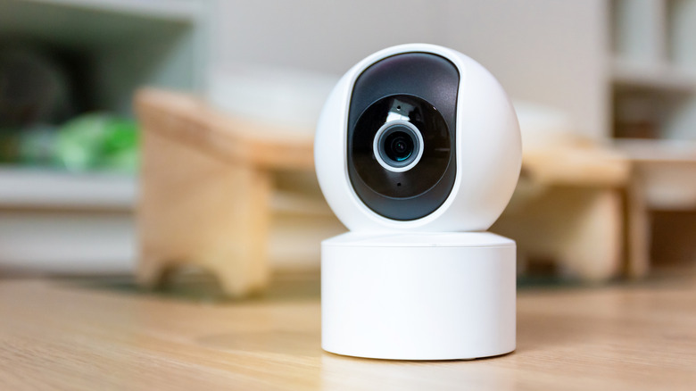 A home security camera on a wooden surface.