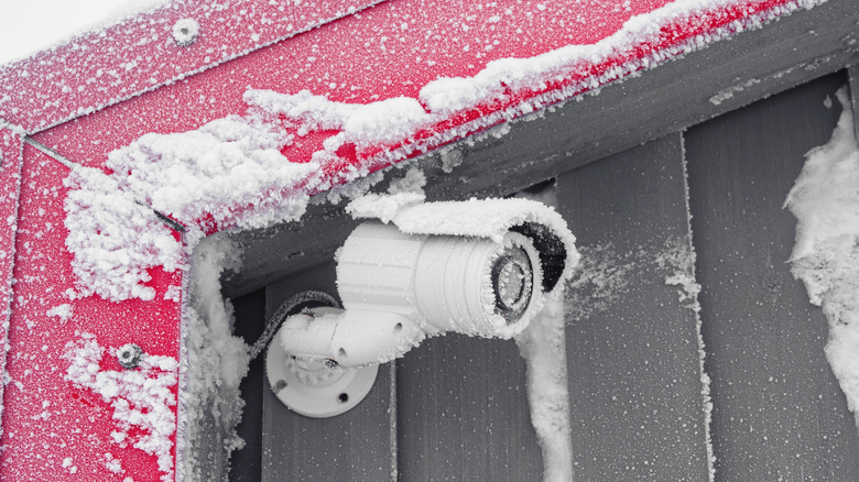 A security camera installed outdoors, covered in snow.