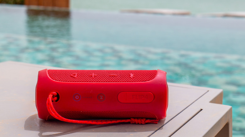 A Bluetooth speaker on a table on the edge of a swimming pool.