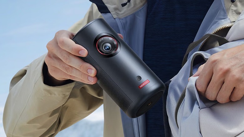 A person placing the Nebula Capsule 3 Laser portable projector in a backpack.