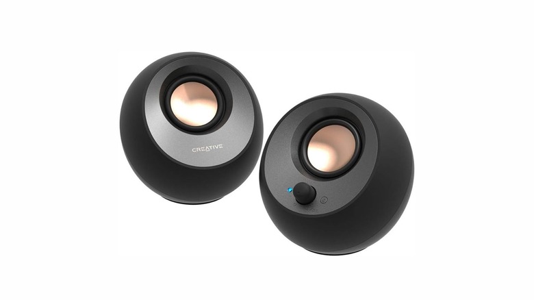 Two orb-shaped speakers colored black. The right speaker has a volume knob and the left one has "CREATIVE" written on it.
